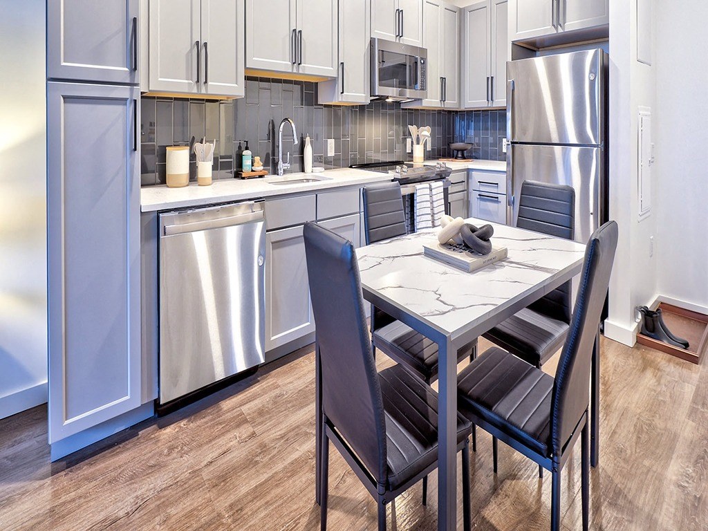 a kitchen with stainless steel appliances and a table and chairs